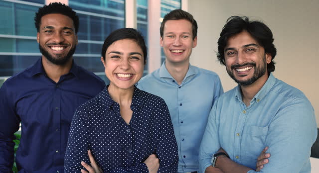 Four multinational employees smiling staring at camera