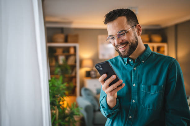 istock One man with eyeglasses stand at home use mobile phone sms texting 2066267895