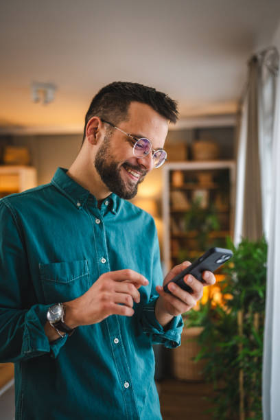 istock One man with eyeglasses stand at home use mobile phone sms texting 2066270997