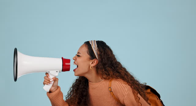 Megaphone, student anger and woman protest democracy vote, government transformation or human rights rally. Studio speech, microphone and speaker voice opinion, revolution or yell on blue background