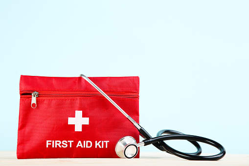 First aid kit with stethoscope on mint background
