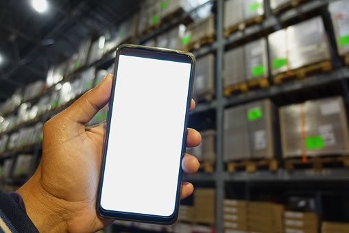 business owner holding phone mock up in warehouse