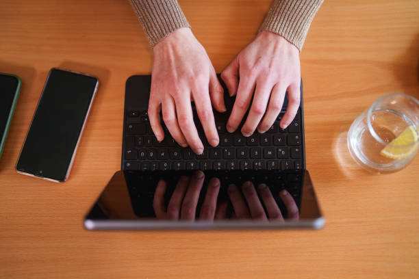 Clouse up to hands typing on digital tablet.