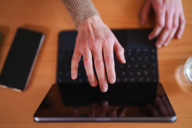 Clouse up to hands typing on digital tablet.