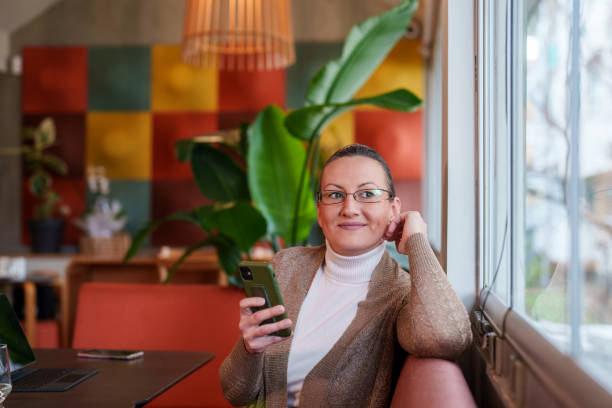 istock Woman sitting on a table at the cafe, using mobile phone. 2066402864