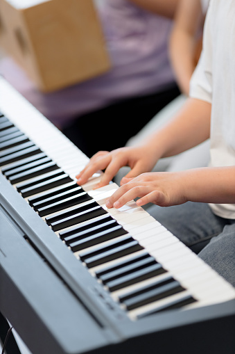 A close-up image capturing the tender hands of a child playing a piano, evoking a sense of learning, passion, and the beauty of music