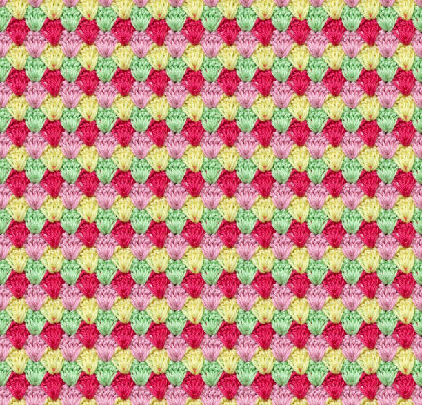 Seamless knitted texture in the form of flower buds. The pattern is crocheted from multicolored cotton yarn. Bright summer range of shades.