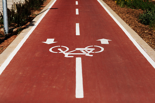 New marking bike path. White bicycle symbol and two oposite arrows on red asphalt lane, road. Bicycle path in the city. Two-way cycle lane on an avenue. Lifestyle. Urban traffic and transportation.
