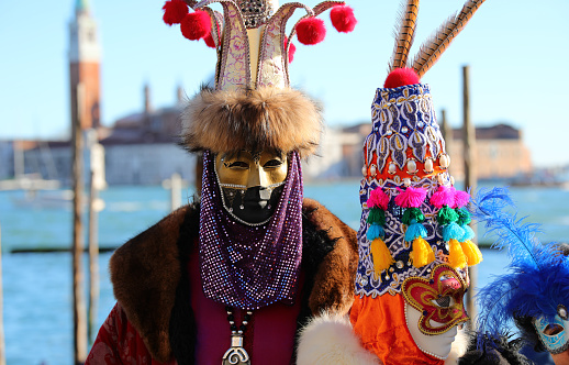 Venice, Veneto, Italy - February 19, 2020: Carnival mask couple portrait on San Marco square waterfront.