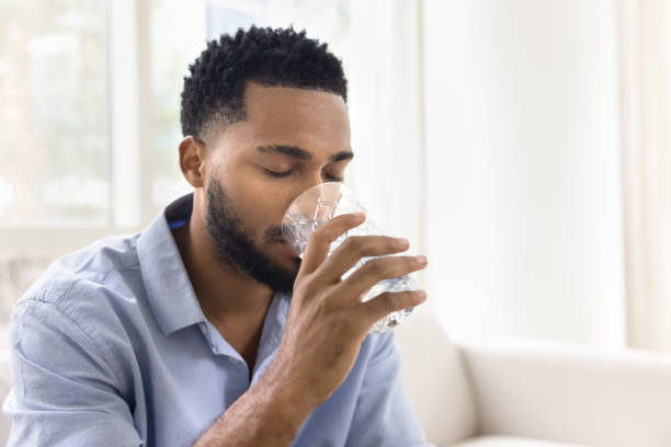 istock Calm thirsty young African man drinking fresh clear water 2066463381