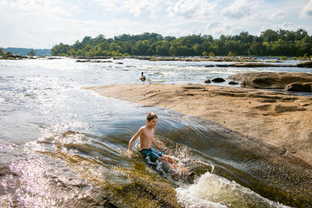 istock Teenage boy swimming in river rapids 2066475895