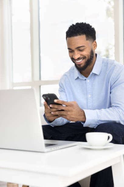 istock Positive happy young Black freelancer man typing on mobile phone 2066502572