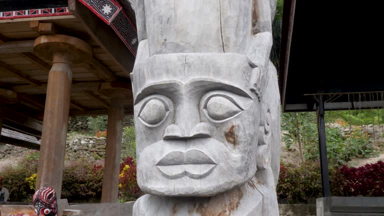 Carved Toba Batak totem pole on Samosir Island, vibrant flora background, cultural artifact