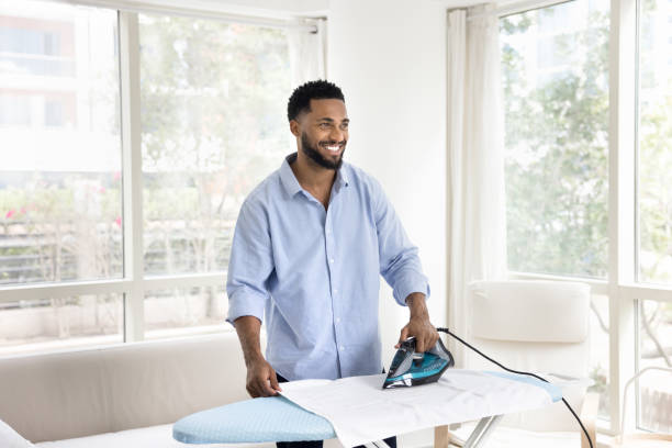istock Happy handsome young African man ironing fabric, linen at home 2066532281