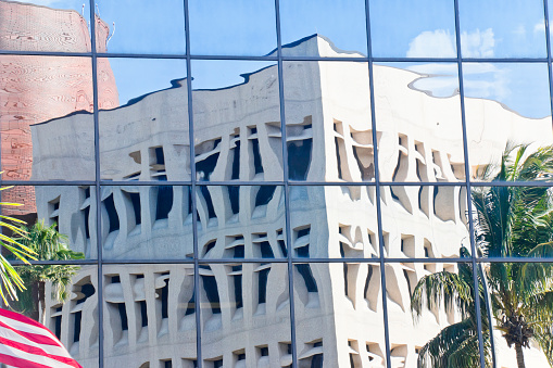 Reflection of a highrise building in the glass facade of an office building and US flag in downtown Fort Myers, Florida, USA.