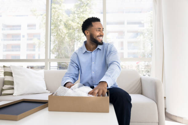istock Positive young African American customer guy unpacking parcel at home 2066557374