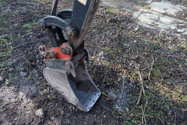 Bucket of a small excavator standing on the ground. Close-up.