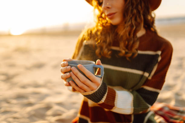 istock Young woman drinking morning coffee on the beach. 2066576321