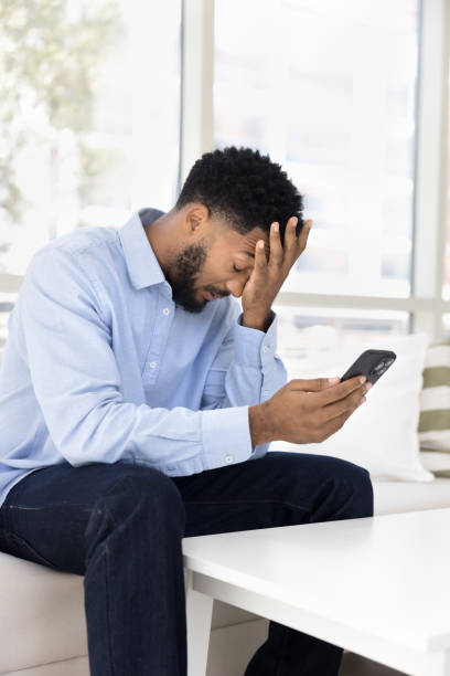 istock Tired frustrated young African man having problems with mobile phone 2066582108