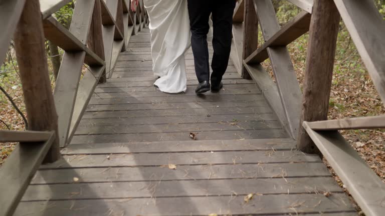 The feet of the bride and groom walk along the wooden steps.