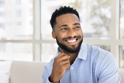 Happy handsome young African American business man looking away, showing healthy white teeth, touching chin. Successful manager, professional, businessman, entrepreneur casual portrait