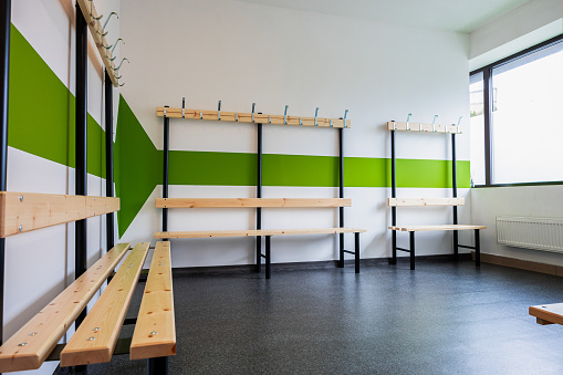 Modern Locker Room with Vibrant Green and White Striped Walls, Wooden Benches, and Coat Hooks