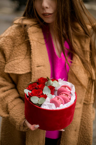 istock Cute woman holding a round gift box with roses and macaroons 2066641624