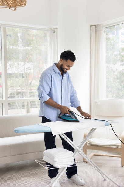 istock Happy young African homeowner man ironing white towels 2066643707