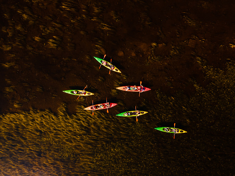 vibrant kayaks on a dark river weaving through natural underwater patterns