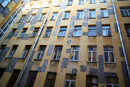 View from below of old courtyard yellow wall in St. Petersburg, Russia. Wall, windows, tubes