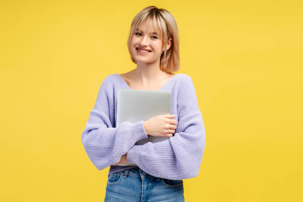 istock Young student woman standing isolated on yellow, carrying laptop computer, smiling 2066670777