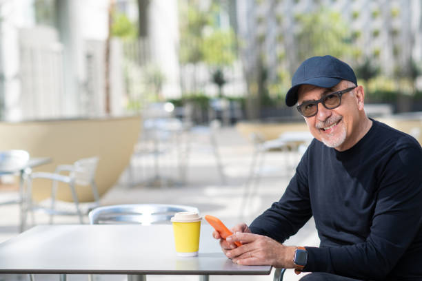 Mężczyzna uśmiechnięty z telefonem i filiżanką kawy – zdjęcie