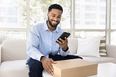 Happy young African American client man typing on mobile phone