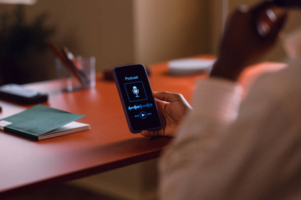 istock Person Holding Smartphone Displaying Podcast Screen on Desk 2066722091