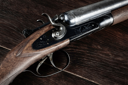 Antique 12 gauge break action smooth bored shotgun on wooden table.