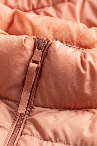 Padded coat in pink color with zipper. Close up of detail and fabric texture