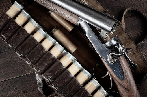 12 gauge break action smooth bored double barreled side shotgun with cases on wooden table.