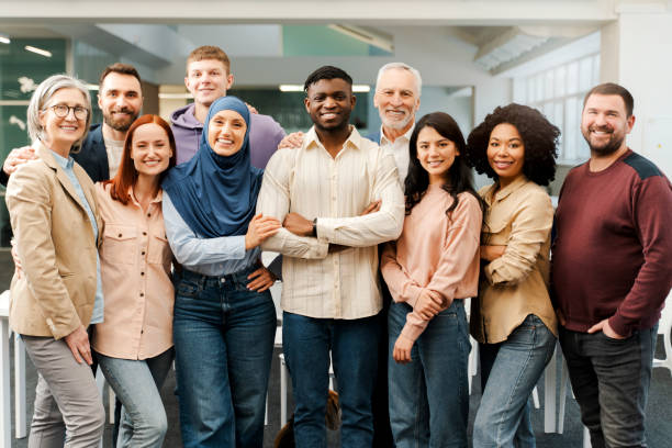 Group portrait of smiling multiracial business people looking at camera in modern office. Meeting Group portrait of smiling multiracial business people looking at camera. Confident workers, colleagues standing in modern office. Meeting. Successful business, career, startup team group of people standing together stock pictures, royalty-free photos & images