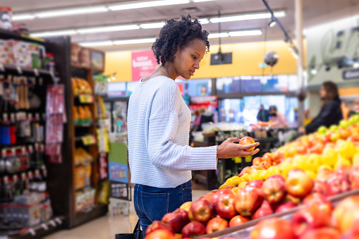 A young black woman looking at produce in grocery store