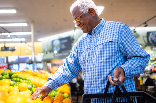 A senior black man looking at produce in grocery store