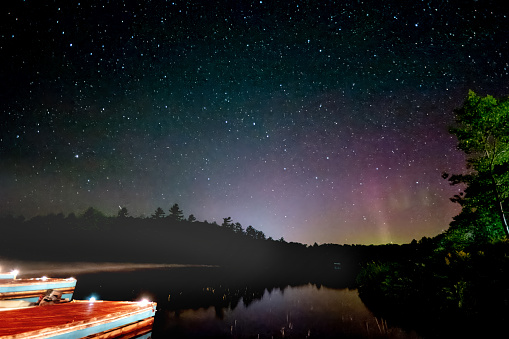 Boats by lake with northern light over the treetop in Muskoka, the cottage country in Ontario