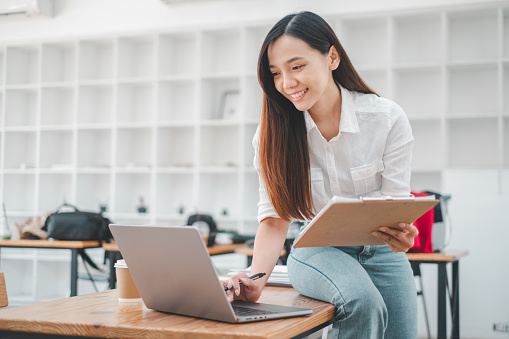 A vibrant entrepreneur adjusts her laptop in a bright workspace, her posture exuding confidence and adaptability, hallmark traits of successful business agility.