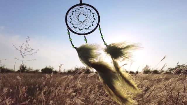 The wind moves the feathers of the dream catcher.