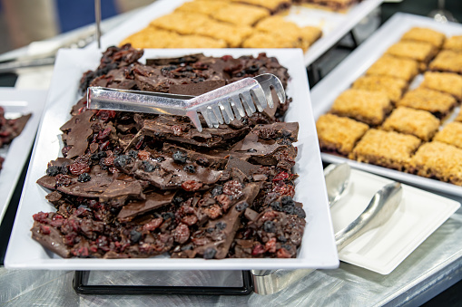 A tray of chocolate desserts with a serving tong on the platter plate catered for snacks at a conference