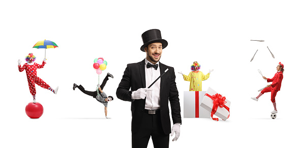 Magician with a wand, mime, clowns and a juggler performing in the back isolated on white background, circus show