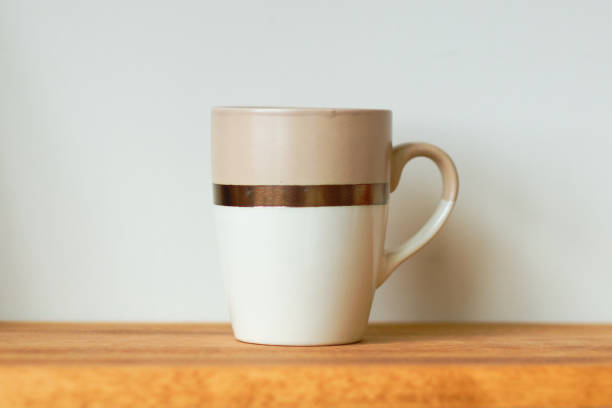 istock A cup on a wooden shelf against a wall background 2067037641