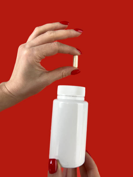 istock Woman holding pill and bottle on red background, closeup. Space for text 2067039891
