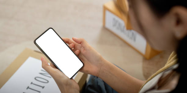 istock Mockup of a woman holding and using mobile phone with blank screen while laying down on the floor with feel relax 2067125602