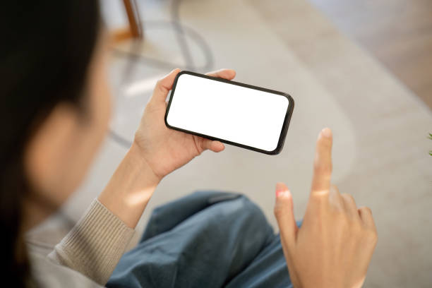 istock Mockup smartphone of a woman holding and using mobile phone with blank screen while on the sofa with feeling relaxed 2067143966
