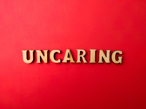 Wooden letters arranged into the word UNCARING on a red background